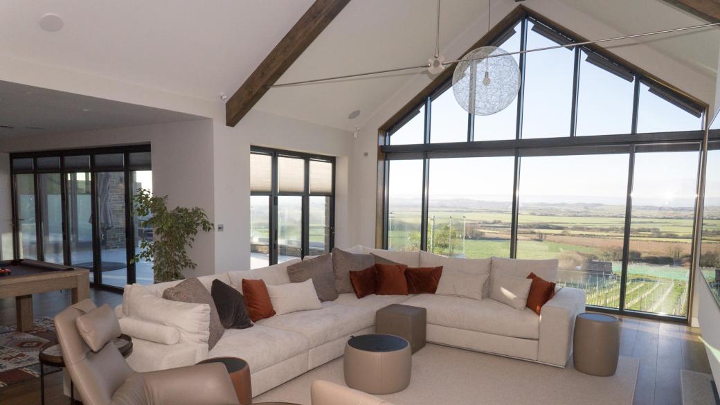 Living area of bespoke luxurious home with panoramic views of Saunton and a large television on wall