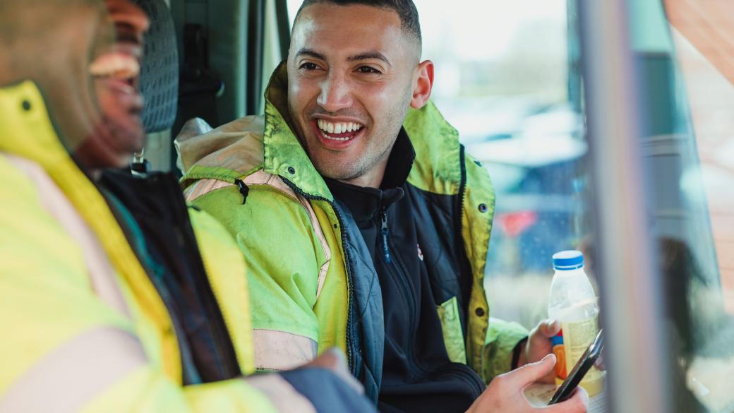 Two builders in a van chatting and laughing