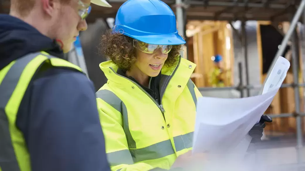 Female surveyor reading paper plans on a construction site
