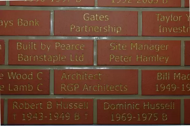 Red Brick Wall with "Built by Pearce Barnstaple Ltd" engraved in gold text