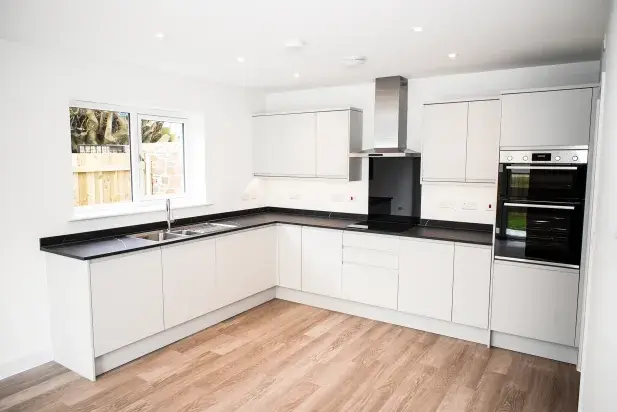 Modern new white kitchen with wood effect flooring in new home at Market Gardens in Torrington