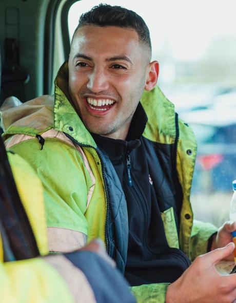 Two builders in a van chatting and laughing