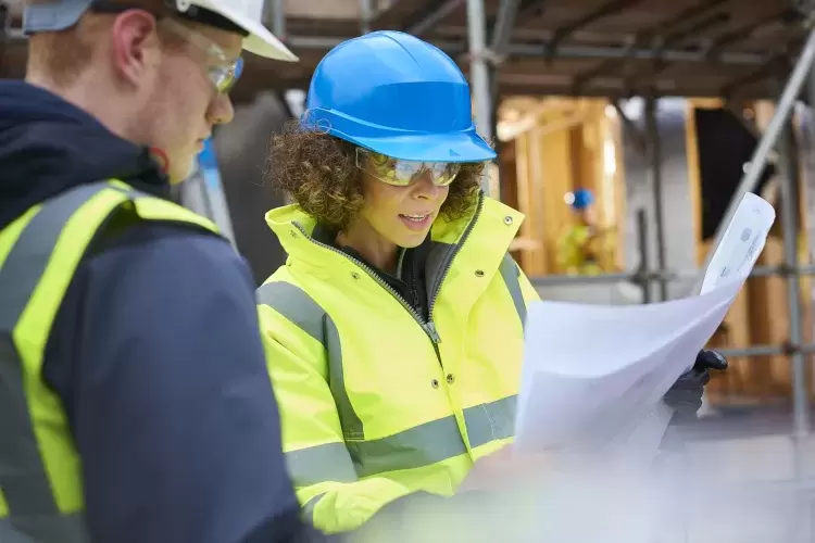 Female surveyor reading paper plans on a construction site