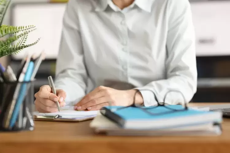 An office worker writing notes with pen and paper