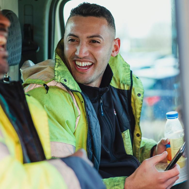 Two builders in a van chatting and laughing