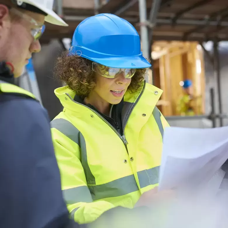 Female surveyor reading paper plans on a construction site